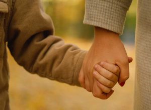 Barn och förälder håller hand
