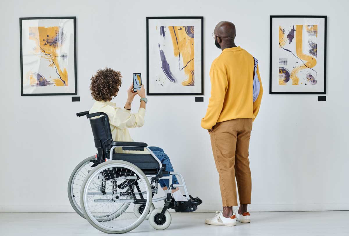 Kvinna i rullstol på konstgalleri. Foto: Envato.
