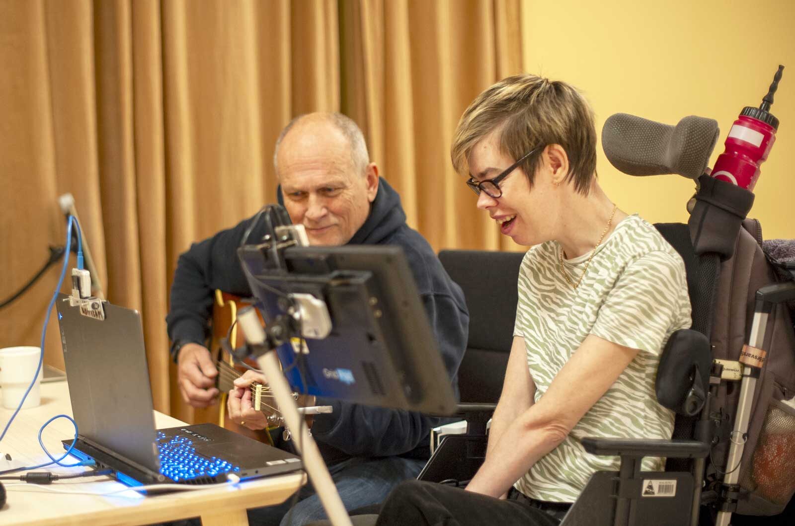 Håkan Larsson kompar på gitarren när Emma Bergdahl testar det nya instrumentet MISK. Foto: Anna Pella
